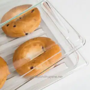 Freshly baked chocolate chip cookies stored in a clear glass container, emphasizing food safety and hygiene practices.