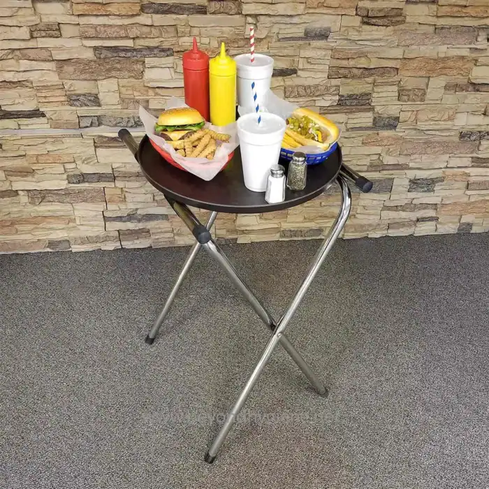 Fresh fast-food meal on a black round tray with ketchup, mustard, salt, pepper, and drinks, set against a stone wall background in a casual dining environment.