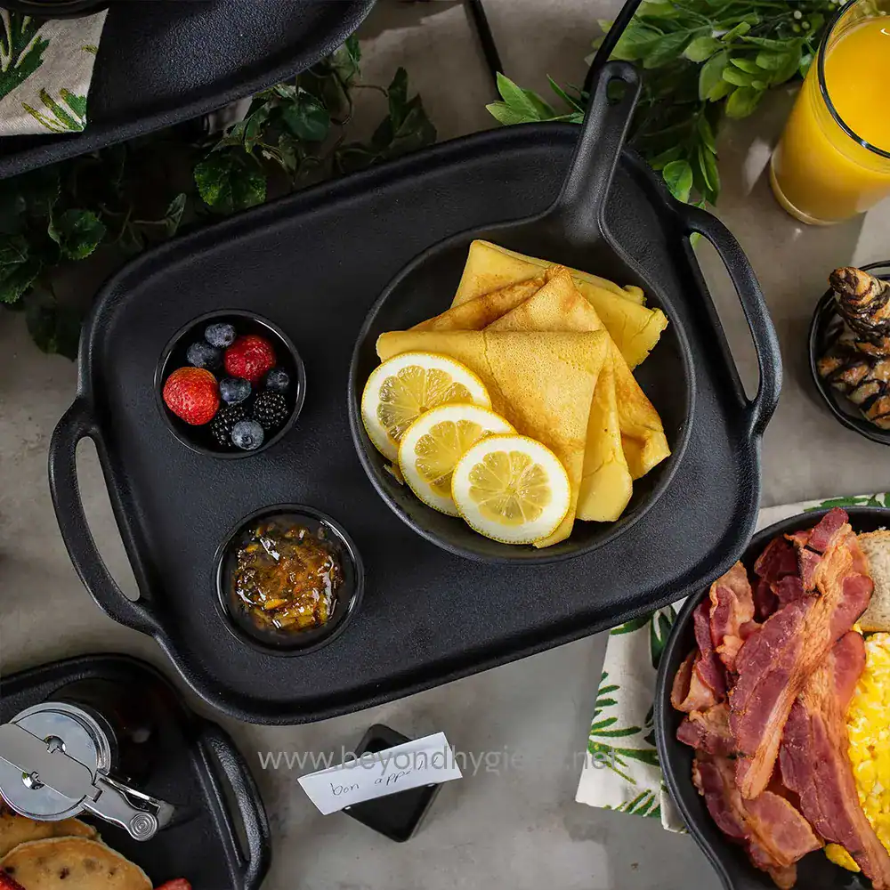8 Delicious breakfast served on a cast iron skillet with lemon slices, crepes, fresh berries, and condiments, emphasizing quality and hygiene for food service establishments.