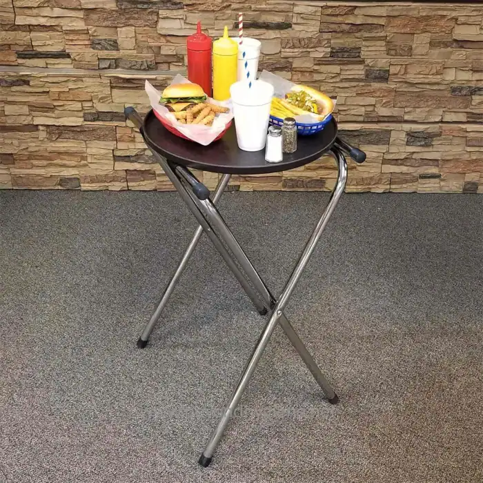 Plastic tray with condiments, ketchup, mustard, and pepper, along with fast food items like fries, burger, and hot dog on a black round table in a casual dining setting.