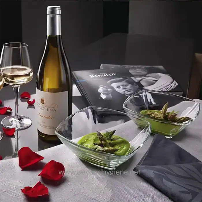 Wine and appetizer setup with champagne glasses, a bottle of wine, seafood, and magazines on a sophisticated table setting.