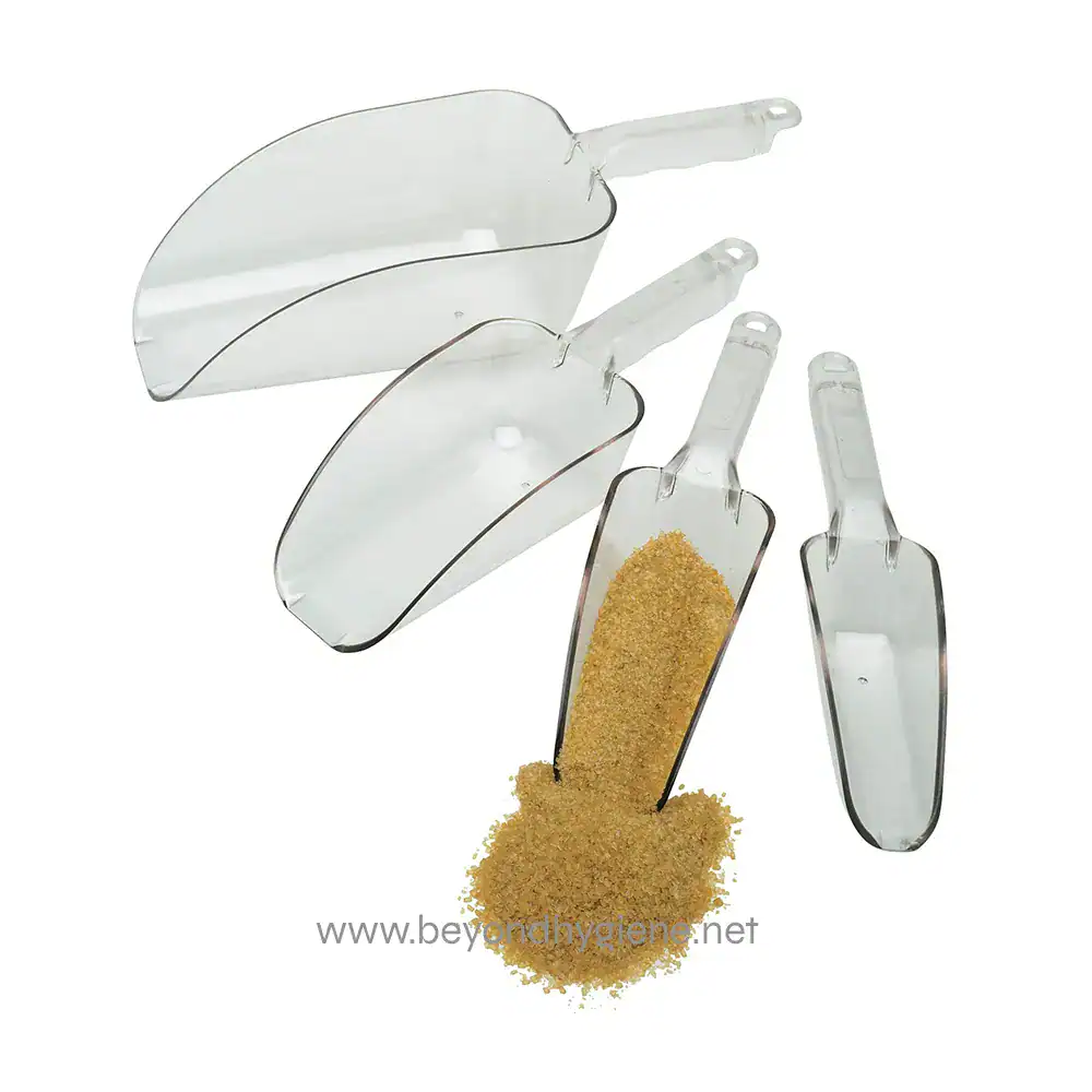 Camwear_Scoops_in_a_Row Dustpan and scoop with brown abrasive powder in a transparent dustpan for cleaning and sanitation in hygiene and janitorial services.