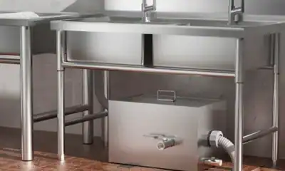 Stainless steel commercial sink with integrated drainage and cleaning station for professional hygienic food processing and cleanup.