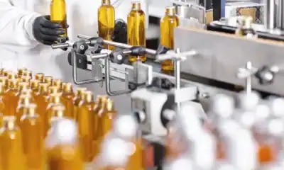 Bottling process in a hygienic manufacturing facility, featuring automated filling of amber glass bottles with cleaning and sanitizing products for Asian markets.
