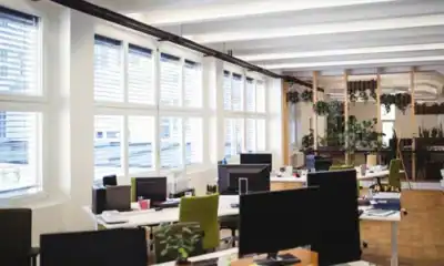 Clean modern office workspace with large windows and computer desks, emphasizing hygiene and cleanliness standards for a productive work environment.