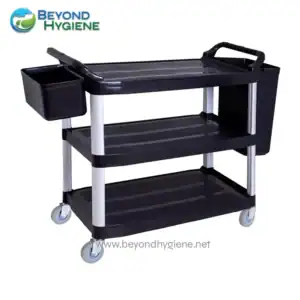 Hygiene service trolley with multiple shelves and side bin for cleaning supplies and tools in healthcare and sanitation facilities.
