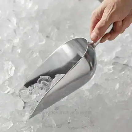 Stainless steel scoop handling ice cubes on a bed of crushed ice for commercial kitchen or restaurant cold storage.