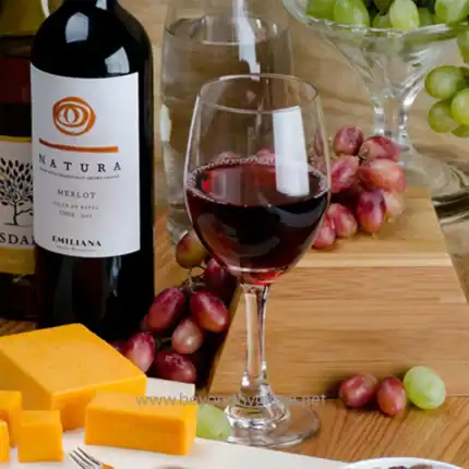 Merlot wine glass with grapes and cheese on wooden table, elegant wine serving, beverage and snack set, Beyond Hygiene Asia promotional image for hospitality and catering services.