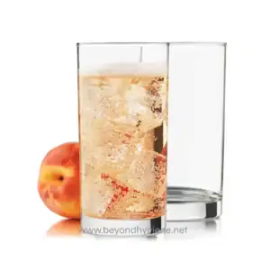 Clear glass of fizzy apple soda with ice cubes and an apple beside it, emphasizing beverages and clean drinking environments.