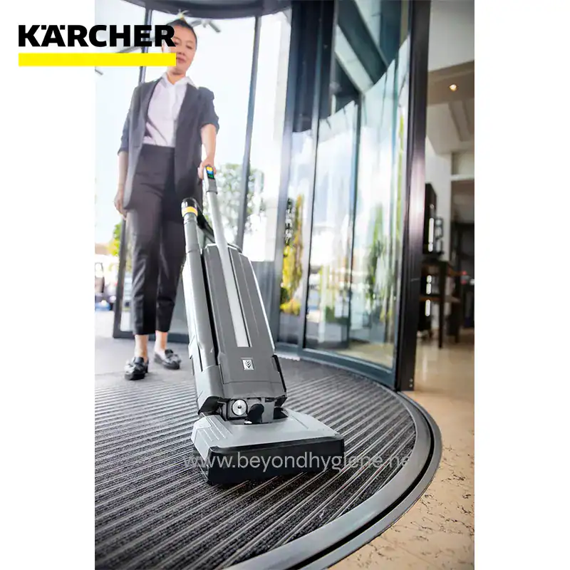 BATTERY POWERED UPRIGHT BRUSH TYPE VAC ( (8) Kärcher cordless commercial carpet cleaner being operated by staff at the entrance of Beyond Hygiene Asia, demonstrating professional cleaning solutions for hospitality and commercial spaces.