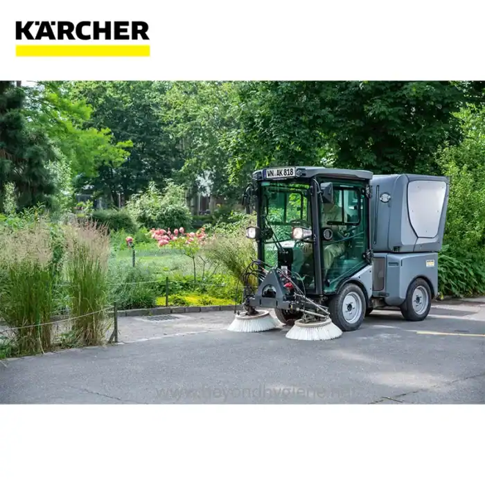 Kärcher street sweeping machine cleaning park pathway in lush garden environment.