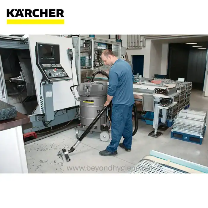 Karcher industrial floor cleaning equipment being operated by a technician in a manufacturing facility, with advanced machinery and cleaning tools.