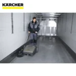 Kärcher industrial floor cleaning machine in a warehouse environment for professional hygiene services.