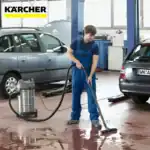 Professional car cleaning service at an auto workshop with industrial vacuum cleaner and hygienic flooring, ensuring spotless vehicle interiors.