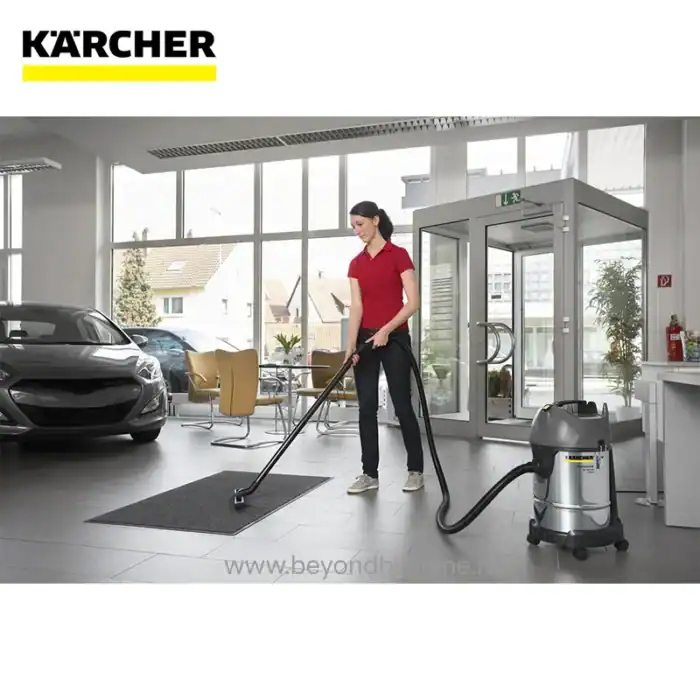 Karcher carpet and floor cleaning machine being used by a woman in a bright, modern car showroom or dealership, emphasizing professional cleaning services and commercial hygiene solutions.