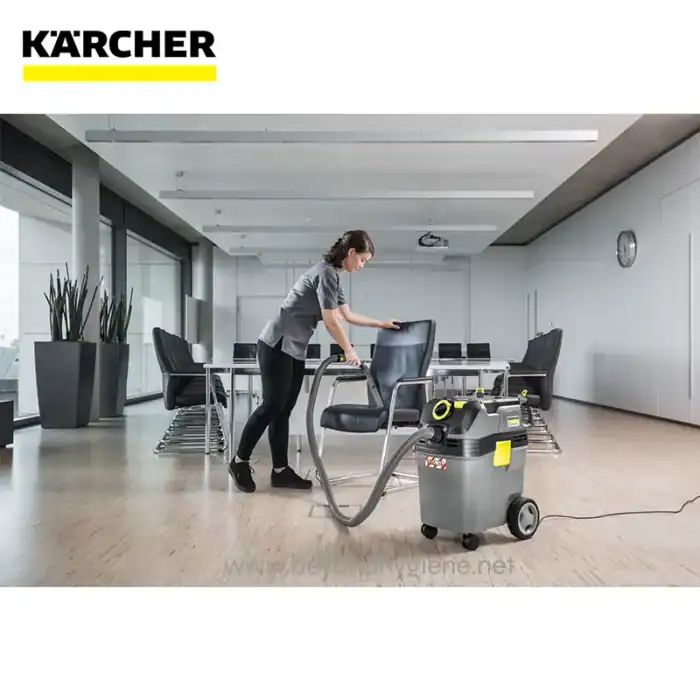 Disinfection service worker using commercial carpet cleaning equipment in modern conference room.