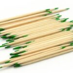 Light-colored matches with green tips, arranged in a scattered pattern on white background.