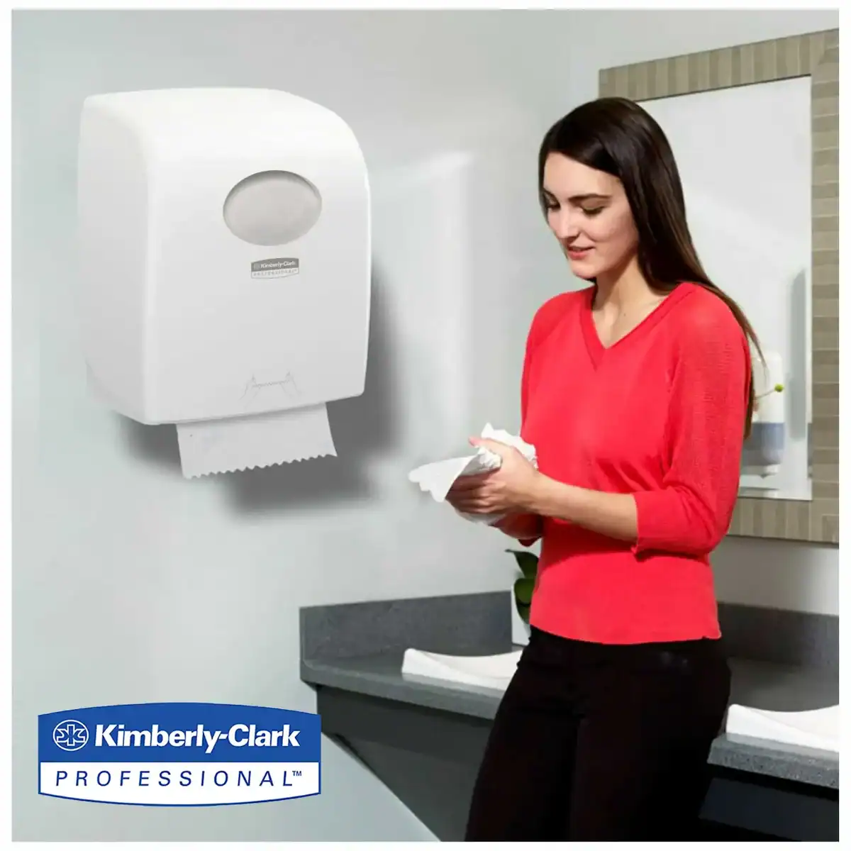 Disinfectant hand sanitizer dispenser in a professional restroom setting with a woman using tissues nearby.