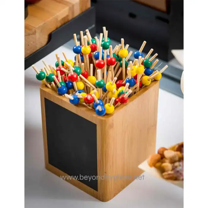 Colorful toothpick and ball cocktail picks in a wooden holder.