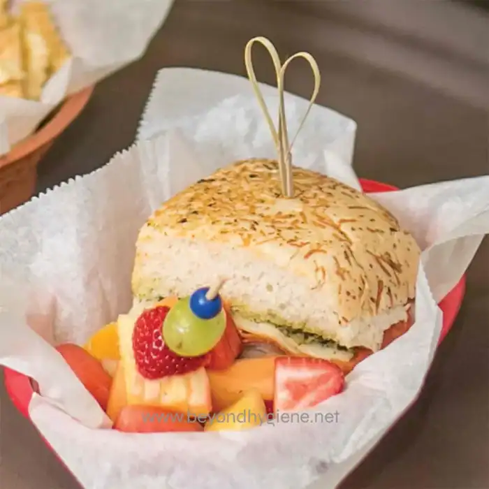 Fresh sandwich with fruit garnish featuring strawberries, melon, and blueberries, served in a paper-lined basket at Beyond Hygiene Asia. Perfect for a quick, hygienic snack.