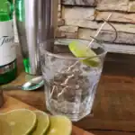 Refreshing glass of ice water with lime slice, mint, and straw on a wooden table, emphasizing hydration and cleanliness, ideal for hygiene and health.