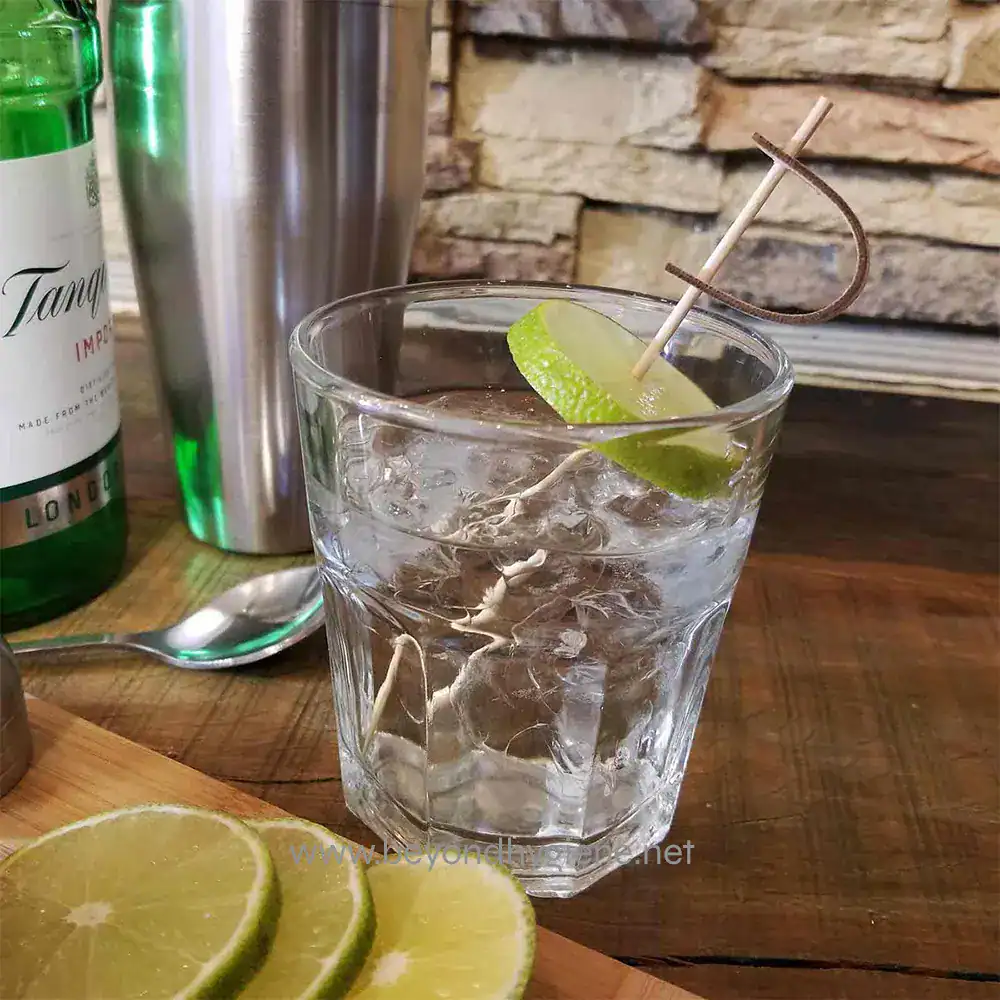 BAMPS45_ENV-01 Refreshing glass of ice water with lime slice, mint, and straw on a wooden table, emphasizing hydration and cleanliness, ideal for hygiene and health.