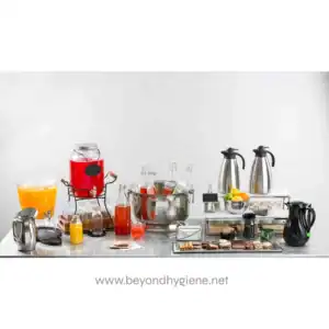 Juice dispenser with beverages and glassware at a catering station, beverage service setup, Beyond Hygiene Asia, event catering, hygienic beverage service, professional food and drink hygiene solutions.