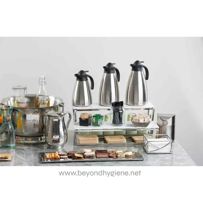 Coffee station setup with stainless steel hot water dispensers and assorted beverages, snacks, and cups for a hospitality or corporate environment - Beyond Hygiene Asia.