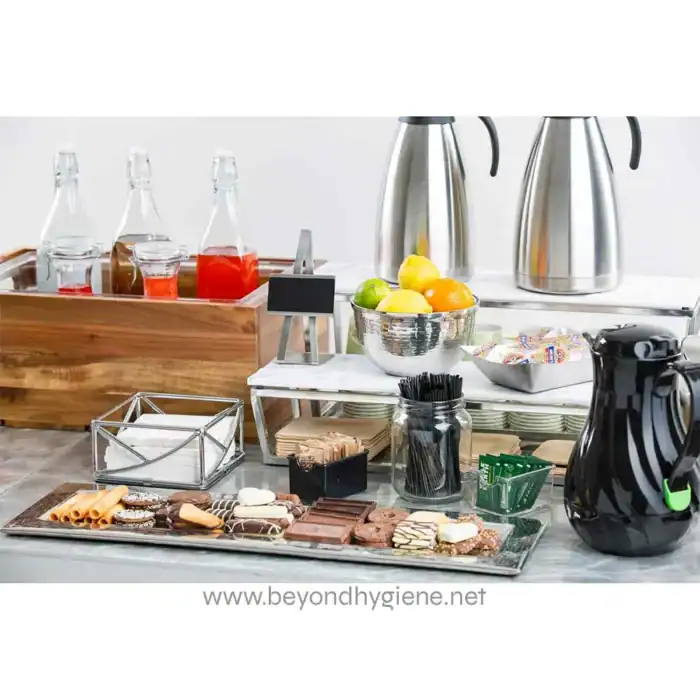 Fresh juice bottles, fruit, snacks, and coffee at a modern beverage station, highlighting hygiene and cleanliness for corporate or hospitality settings.
