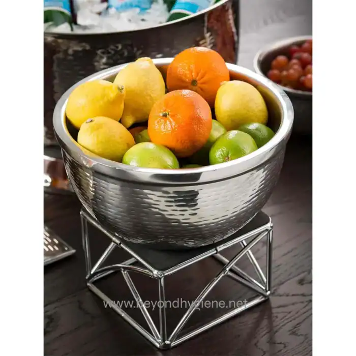 Fresh citrus fruits in a stainless steel bowl on a modern stand, emphasizing hygiene and cleanliness for food safety standards.