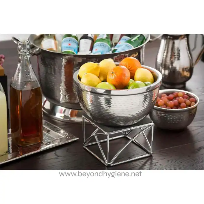 Fresh assorted fruits including oranges, apples, and grapes in stainless steel bowls, set on a dark wooden table for health and hygiene-focused catering at Beyond Hygiene Asia.