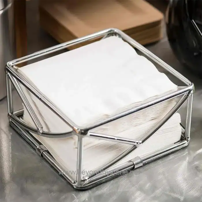 Soft white paper towels stacked in a sleek metal tissue dispenser on a stainless steel countertop. Perfect for hygiene and hand drying in commercial and healthcare settings.
