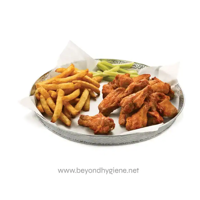 Crispy fried chicken wings with French fries and celery sticks on a metal serving tray.