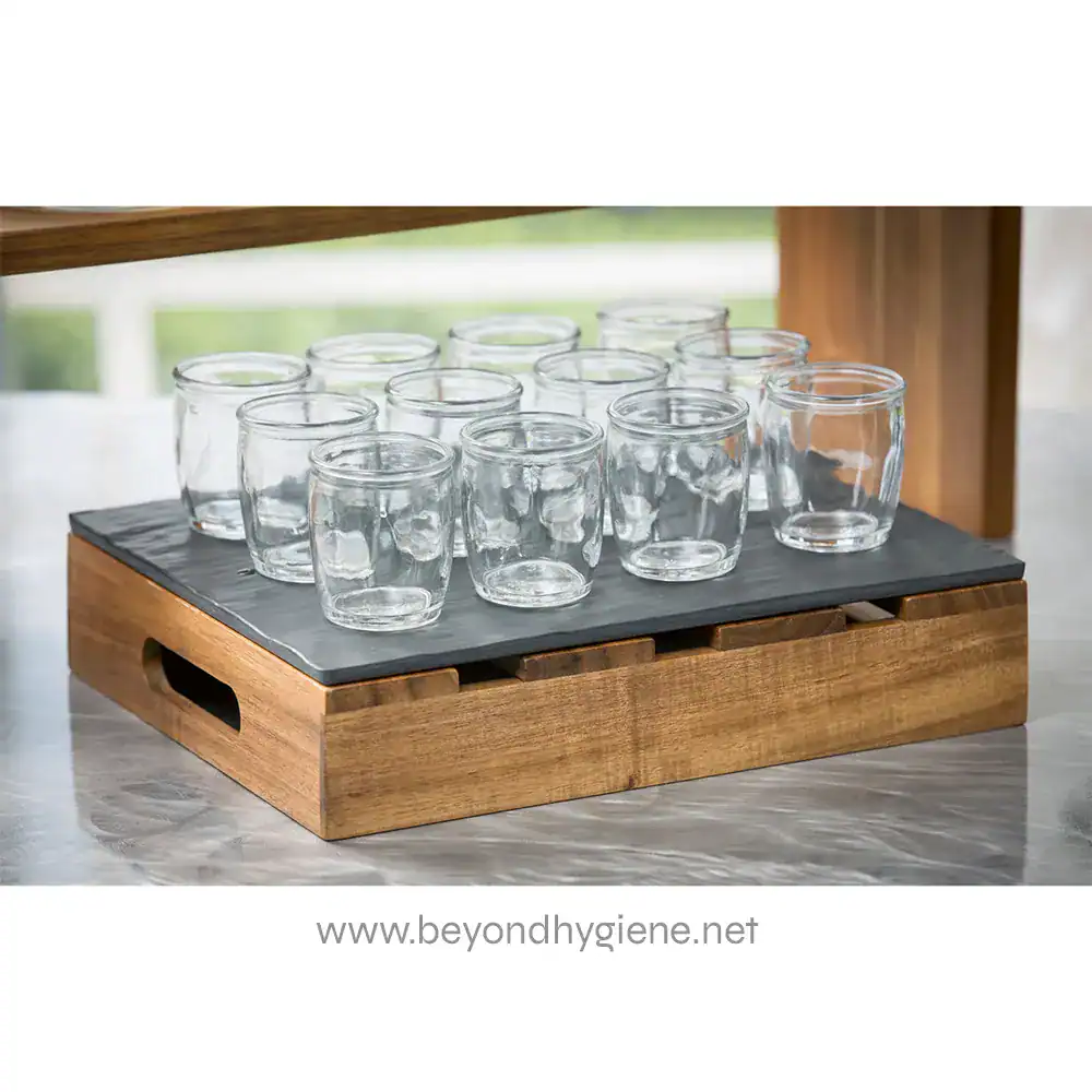 MG1_ENV-011 Clear glass tumblers arranged on a wooden tray with a black base, ideal for hospitality and hygiene-focused spaces.