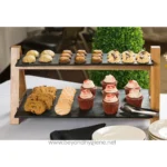 Chocolate chip cookies, cupcakes, and assorted baked treats on a wooden and slate tiered dessert stand at Beyond Hygiene Asia event.