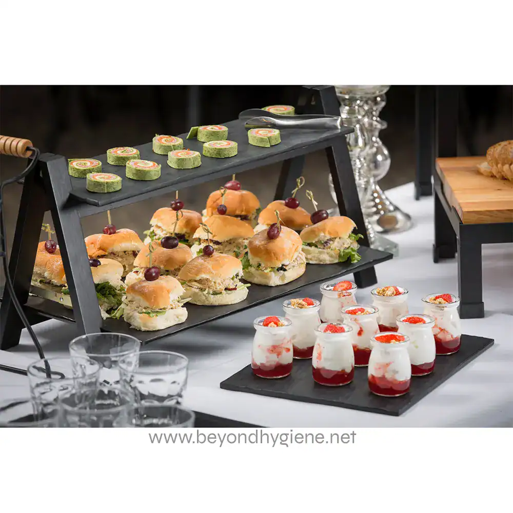 MG1_ENV-05 Mini sandwiches, salads, and desserts displayed on black serving trays at a catering event, emphasizing hygiene and food presentation for corporate or event catering.