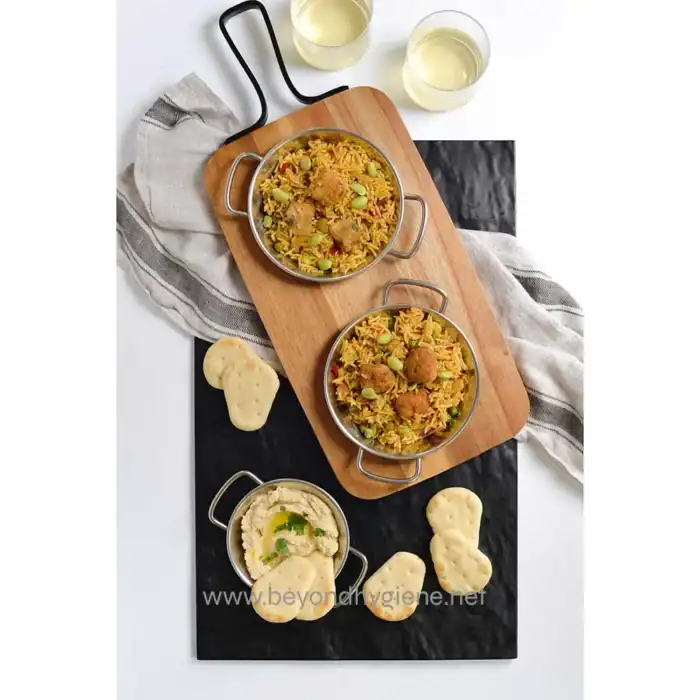 Spiced Indian biryani with fried chicken, served with hummus and naan bread, accompanied by two glasses of white wine on a stylish presentation tray.