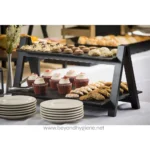 Chocolate chip cookies, cupcakes, and assorted baked goods on a black tiered serving display at Beyond Hygiene Asia event, showcasing catering and food presentation.