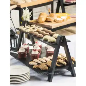 Delicious assorted desserts and baked goods on a black multi-tiered serving stand at a catering event, showcasing professional hygiene standards in food presentation and safety.