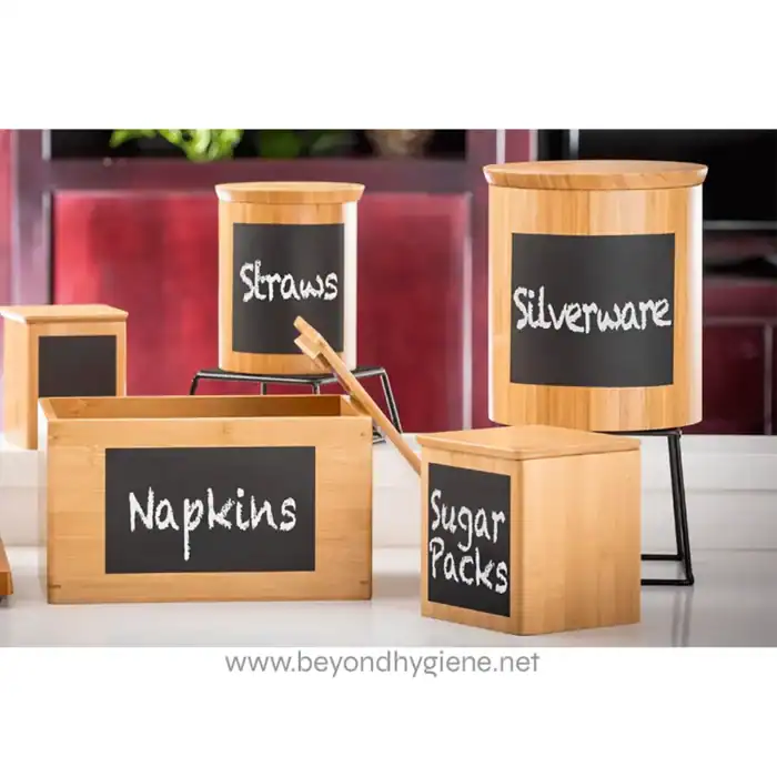 Wooden storage boxes with chalkboard labels for kitchen organization, featuring categories like sugar packs, napkins, straws, and silverware, set in a modern kitchen.